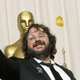 Peter Jackson happily holds aloft his Academy Award in front of a giant Oscar statue.